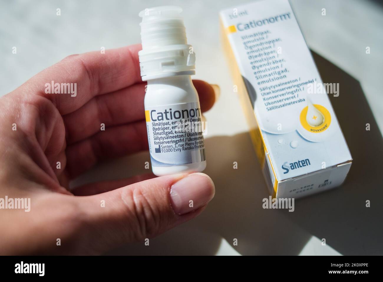Hand holding Cationorm Eye drops by Santen to moisturize and soothe dry, red, itchy or burning eyes. Dry eye syndrome. Stock Photo