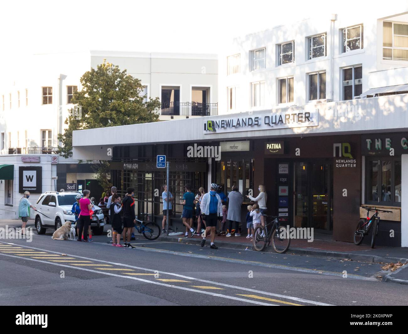 people queue on a pavement and in a road at an urban coffee shop take away during the Covid pandemic in Cape Town, South Africa Stock Photo
