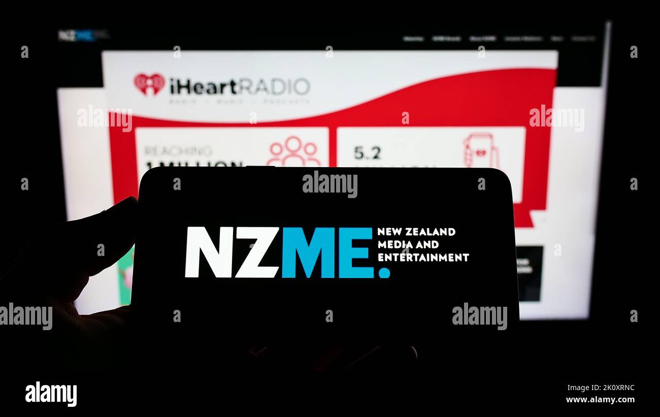 Person holding cellphone with logo of company New Zealand Media and