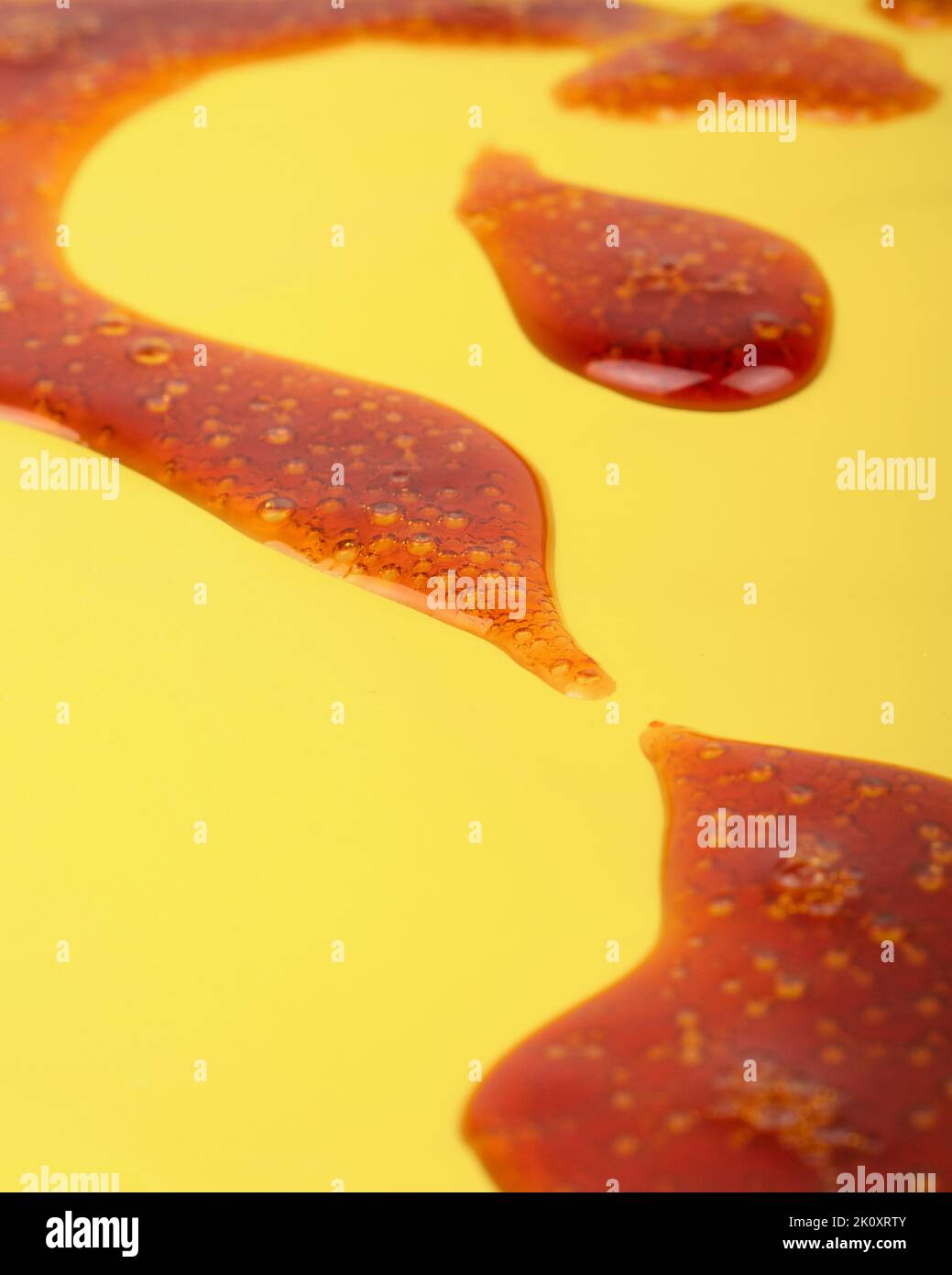 dark cannabis wax concentrate close up, high thc extract resin on yellow background. Stock Photo