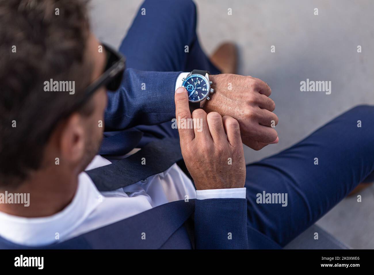 Top view of anonymous businessman in suit checking time on expensive wristwatch while waiting for meeting on city street Stock Photo