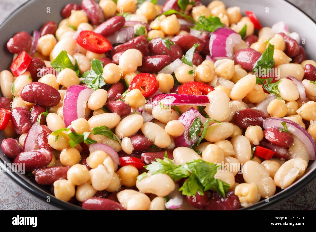 Delicious vegetable salad three beans with chili peppers and red onions close-up in a bowl on the table. Horizontal Stock Photo