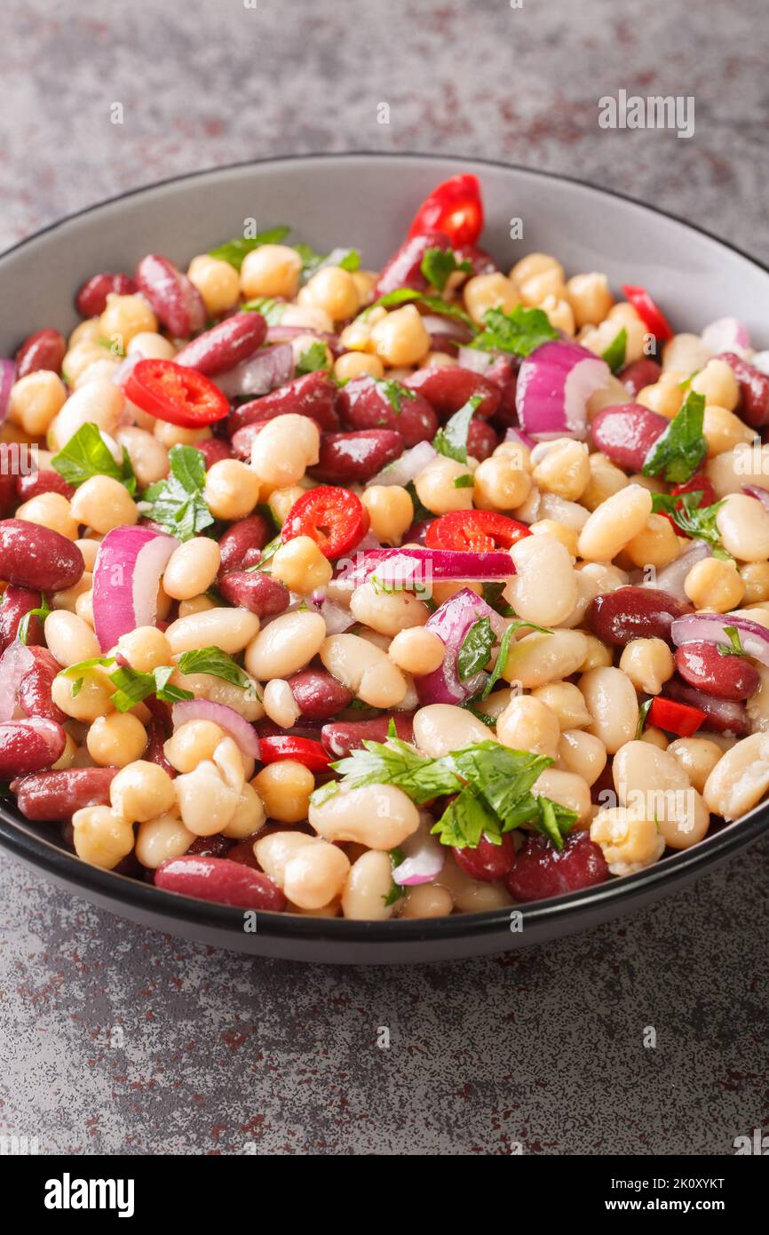 Three bean salad with chili and onion Delicious vegetarian food close-up in a plate on the table. Vertical Stock Photo