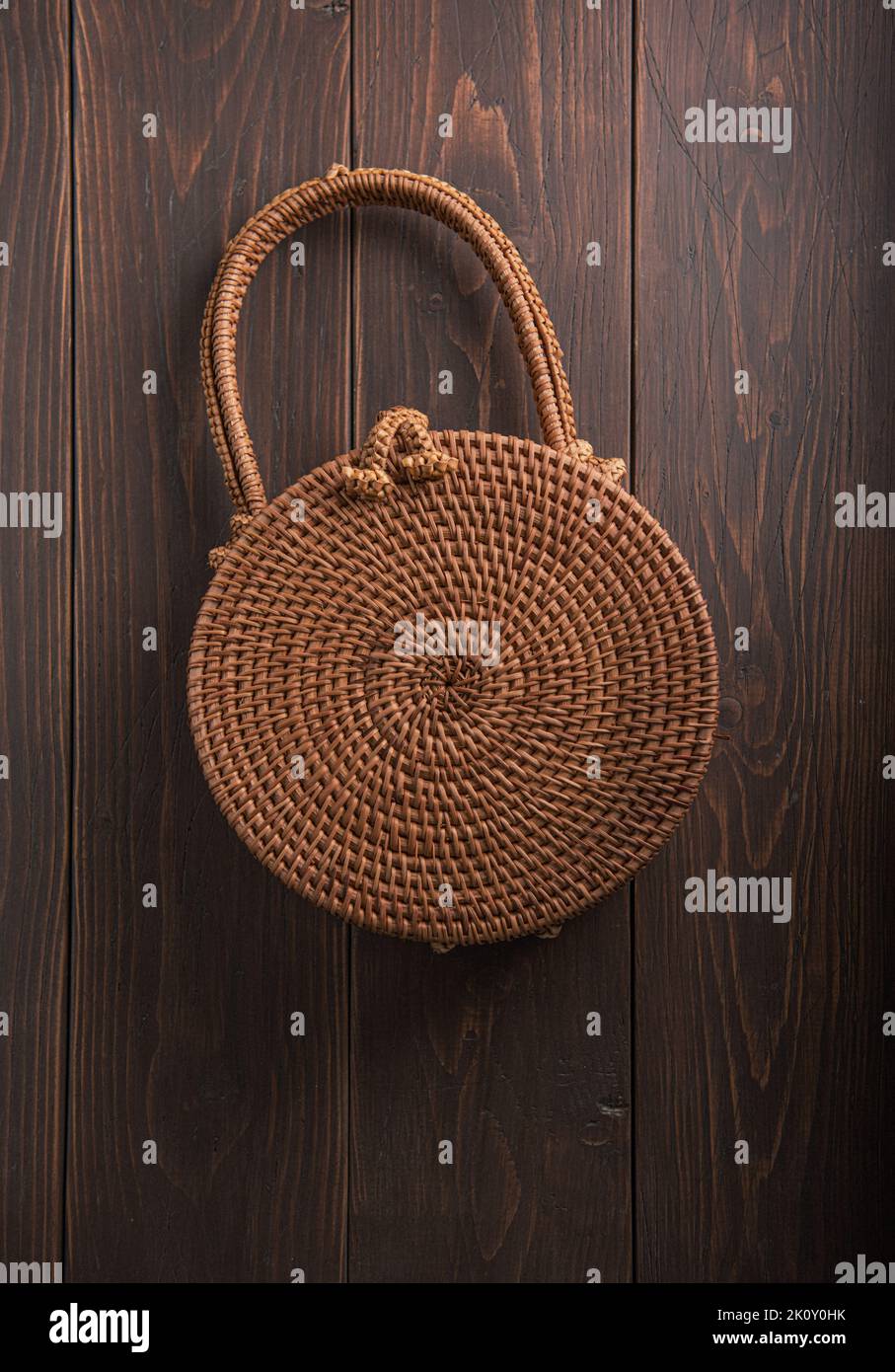 Modern stylish round straw bag on the wooden background, close up Stock Photo