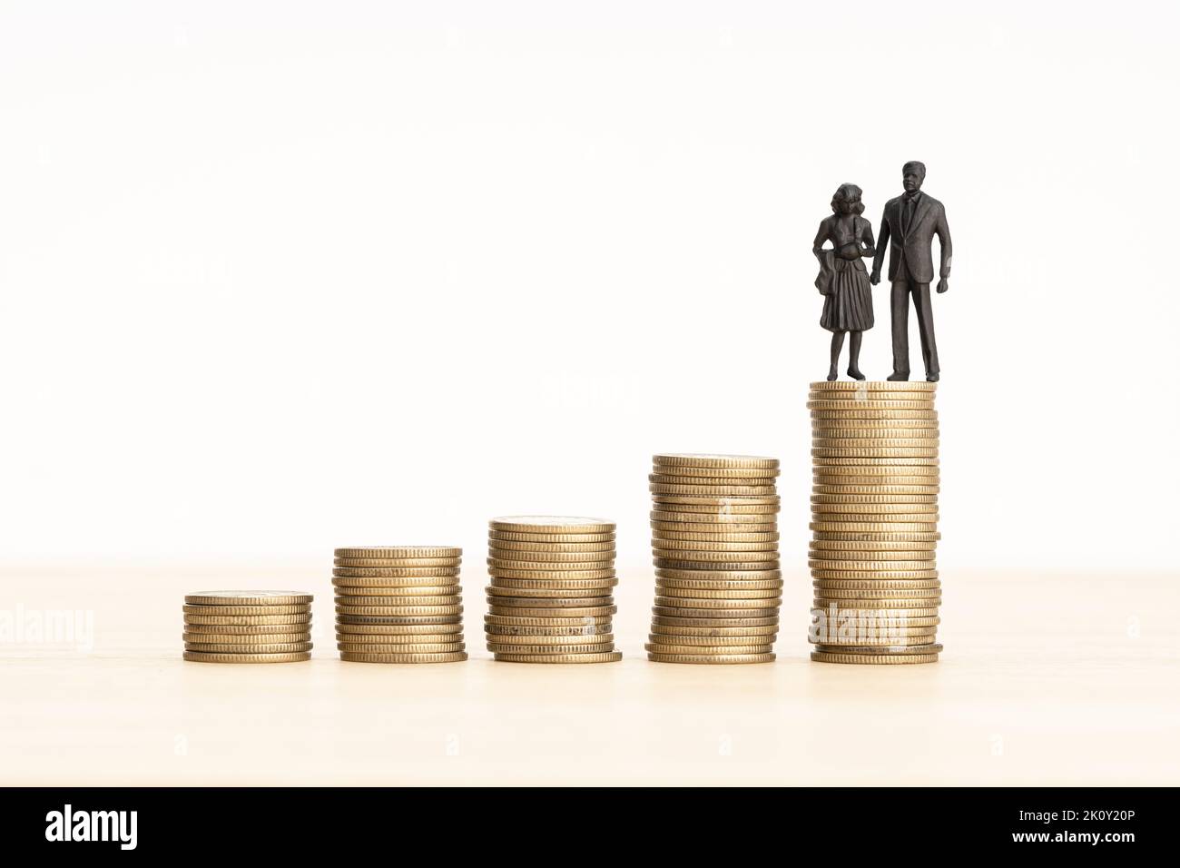 Family Wealth process concept. Couple figurine on Rising Coin stacks. Copy space Stock Photo