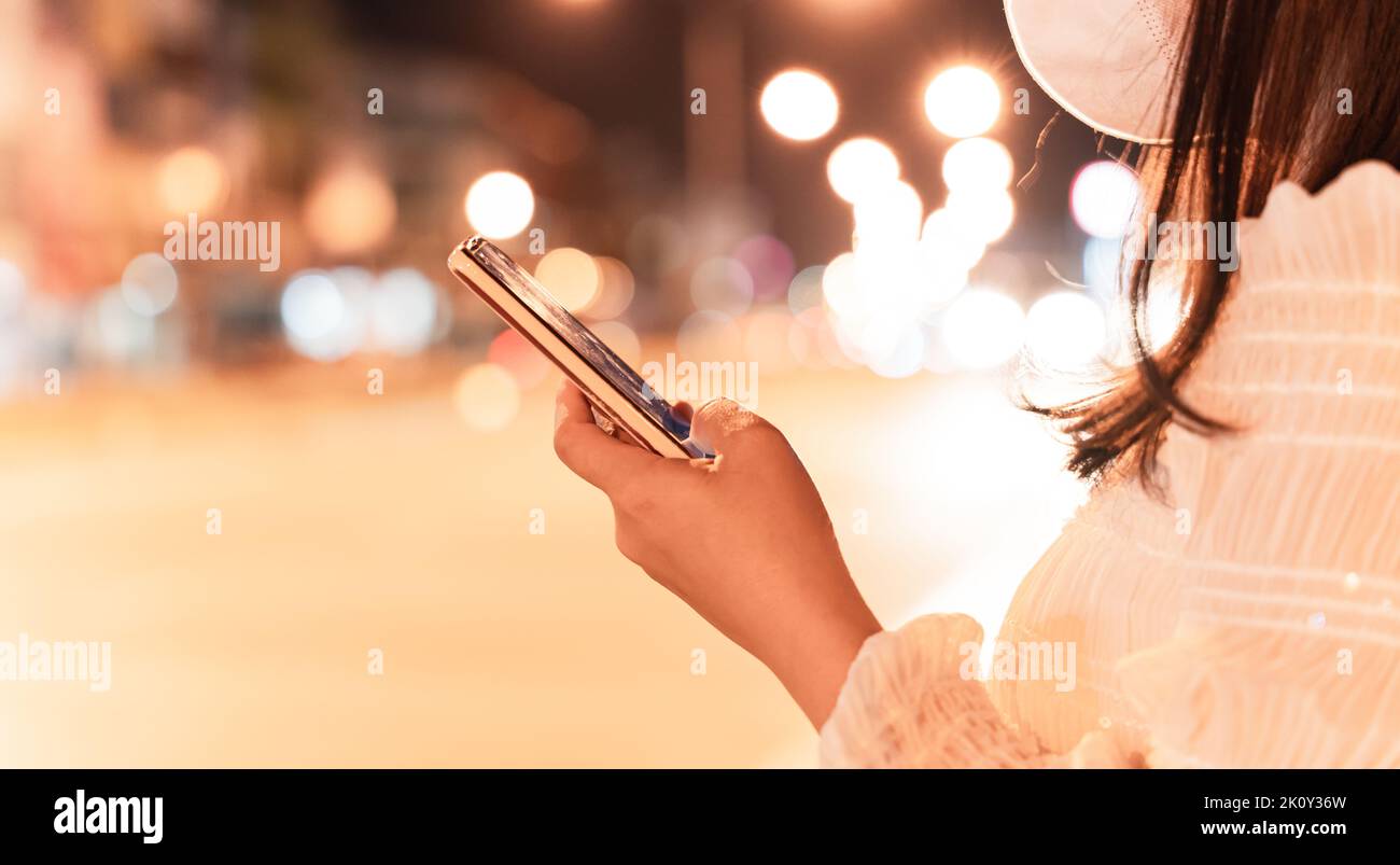 Close-up image of female hand using mobile smartphone at night city street. concept of searching or social networks. Stock Photo