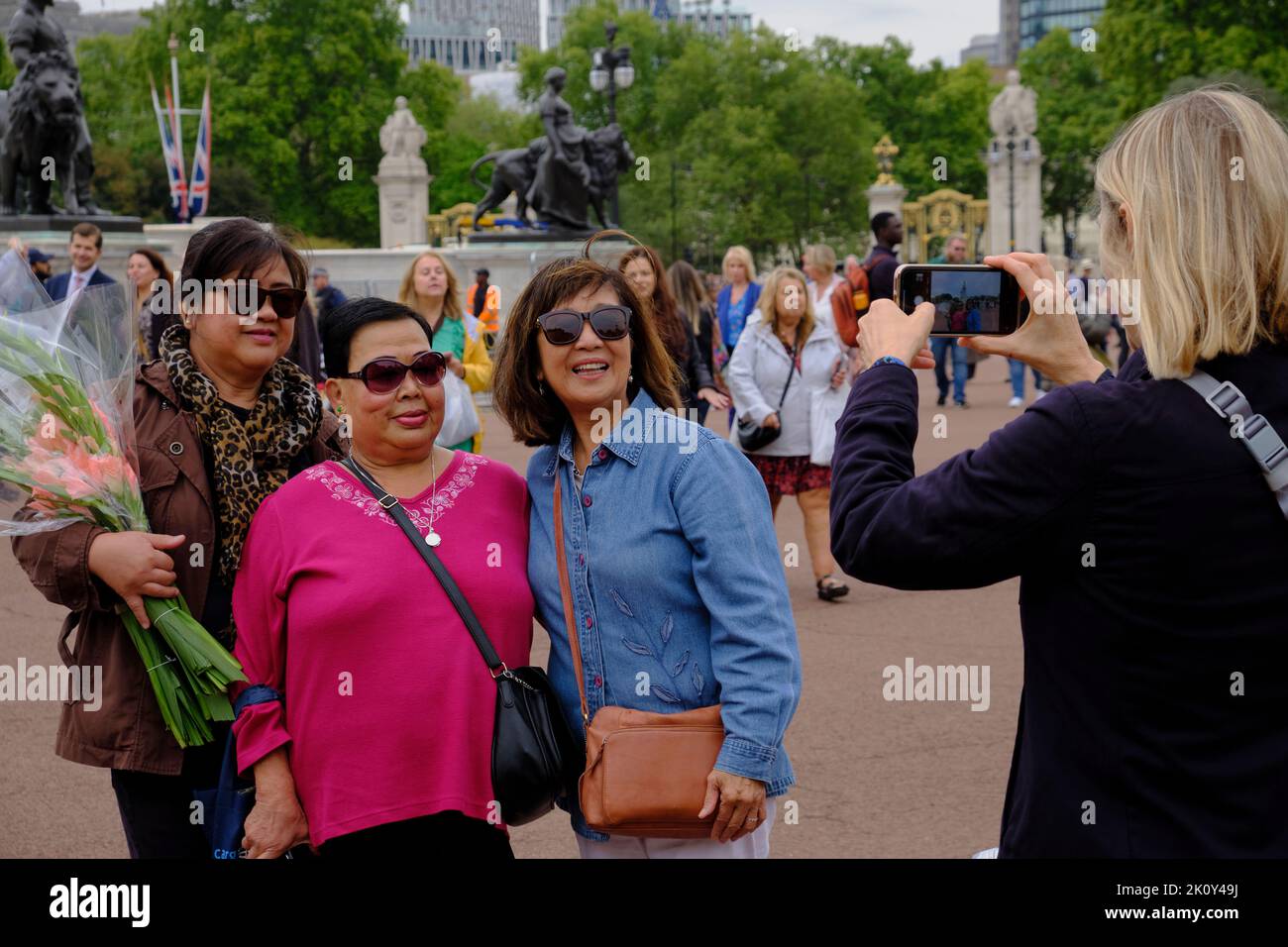Asian Tourists have their picture taken outside Buckingham Palace following the death of the Queen Stock Photo