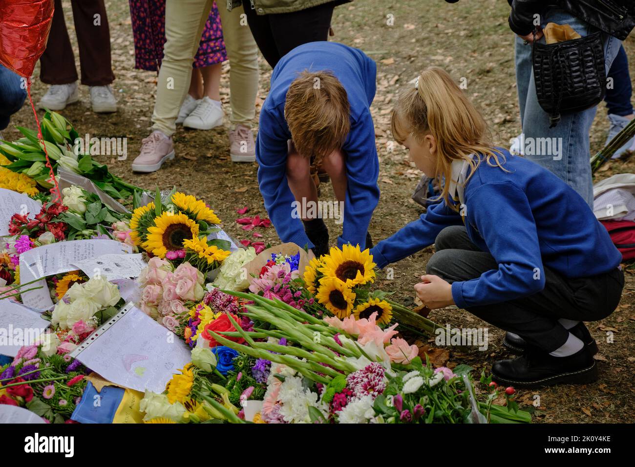 Children bring flowers as part of a floral tribute following the death of the Queen, Green park, London Stock Photo