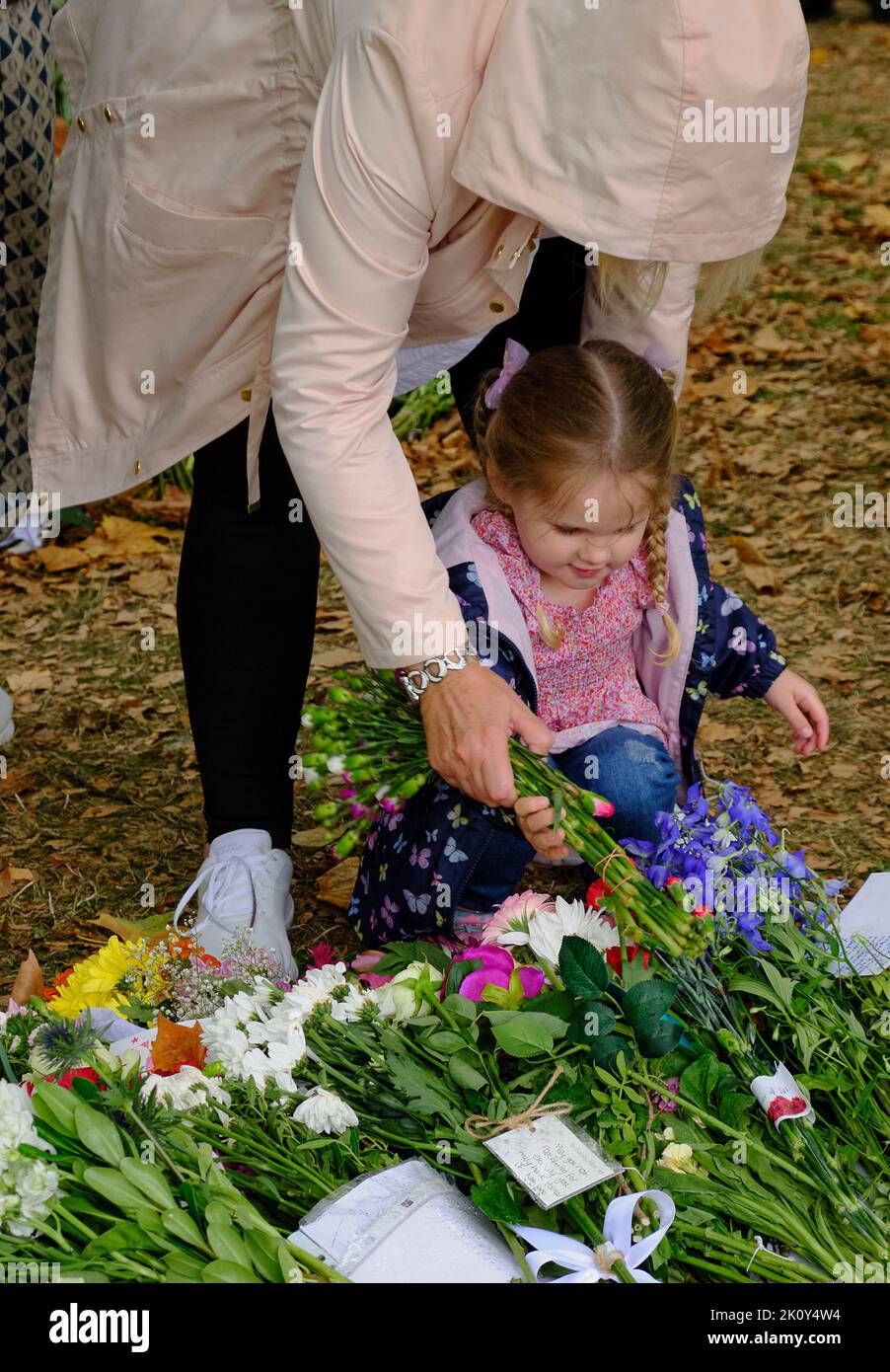Children bring flowers as part of a floral tribute following the death of the Queen, Green park, London Stock Photo