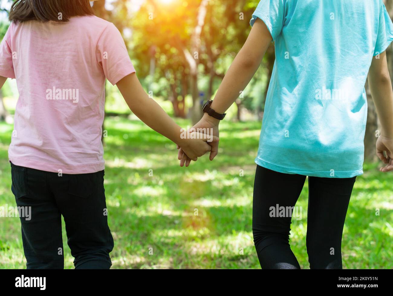 Two sister holding hands in the park in warm spring day. Happy friendship family concept. Stock Photo