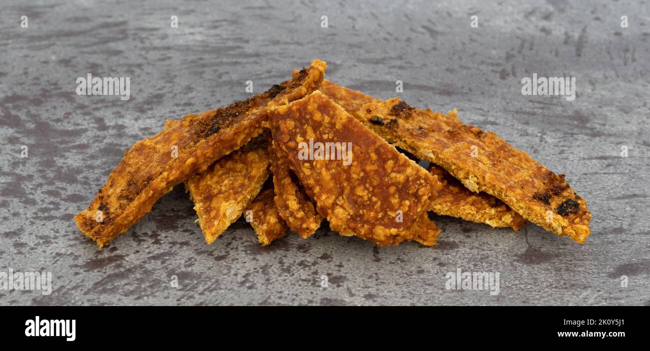 Side view of several slices of duck jerky cut in pieces on a gray mottled background. Stock Photo