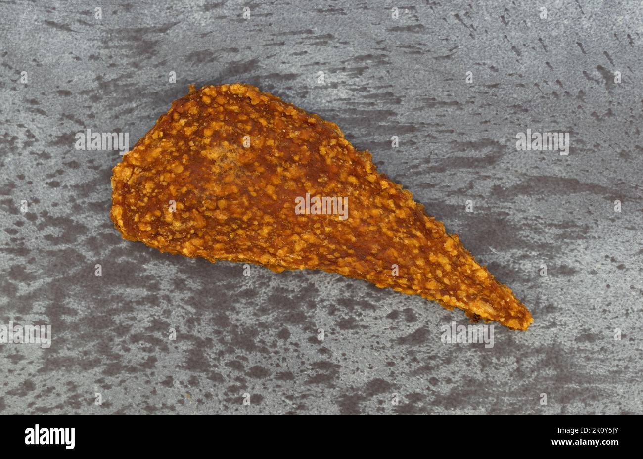 Overhead view of a single slice of duck jerky on a gray mottled background. Stock Photo