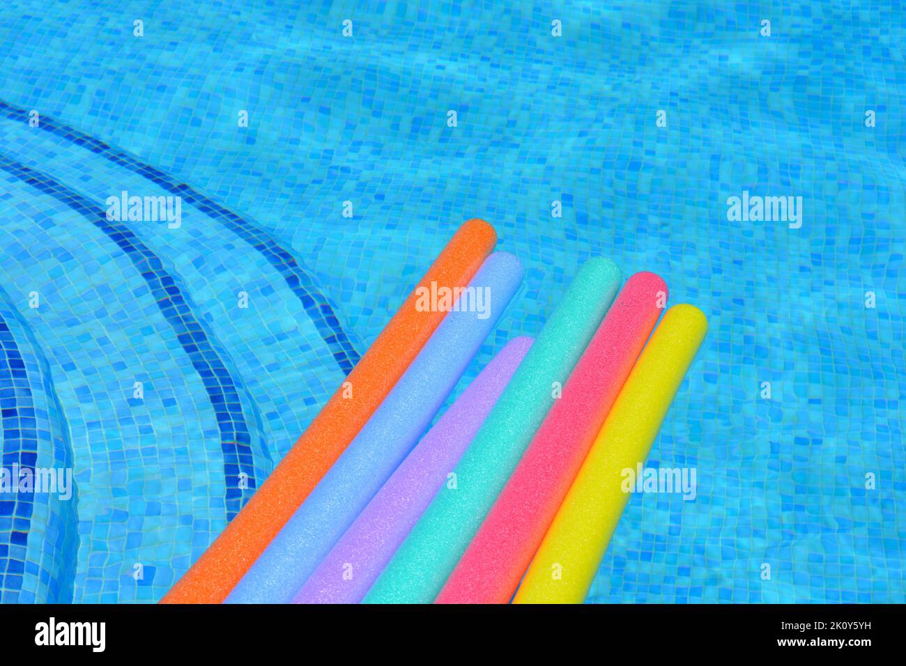 Rainbow coloured pool noodles floating on water in swimming pool Stock Photo Alamy