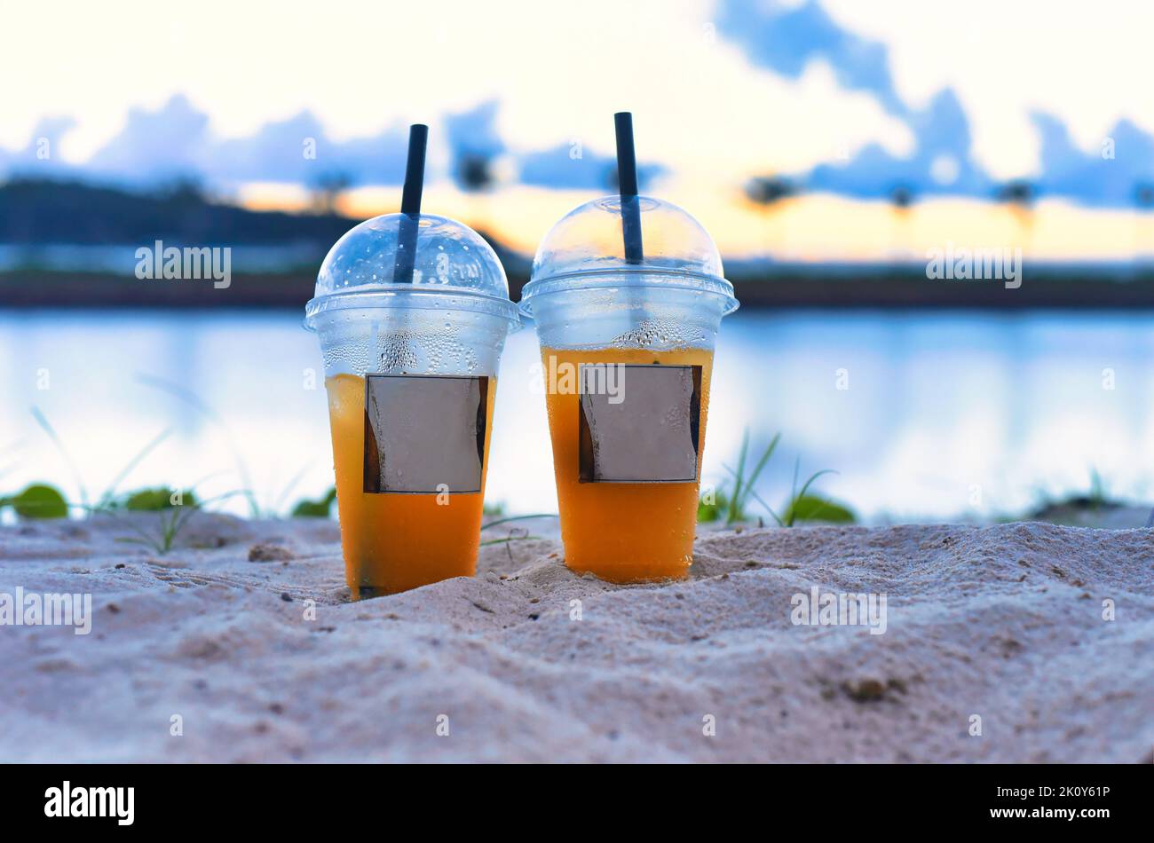 Two plastic cups with iced tea take away against sea Stock Photo