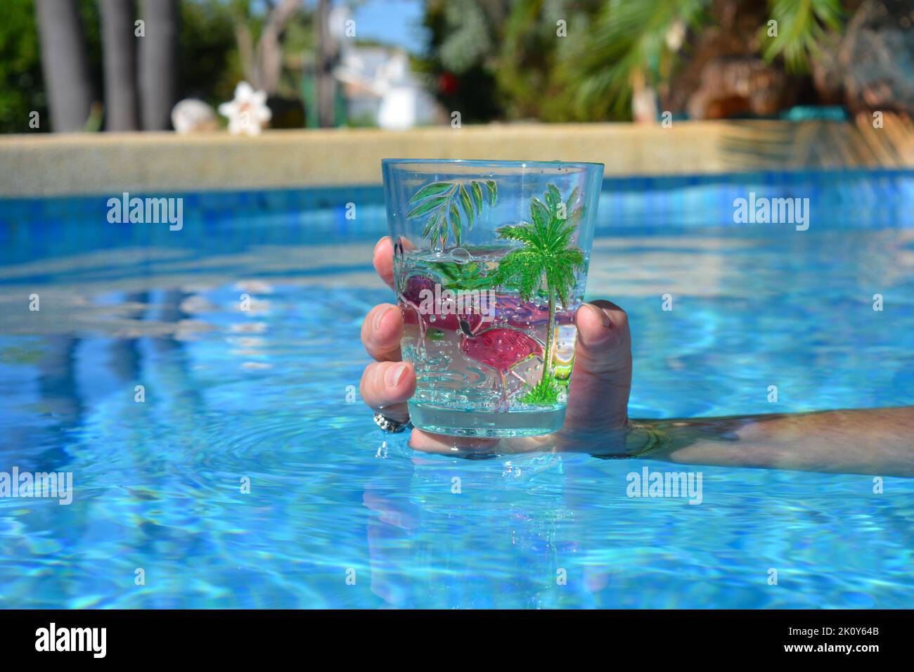 Refreshing drink held in hand, in swimming pool Stock Photo
