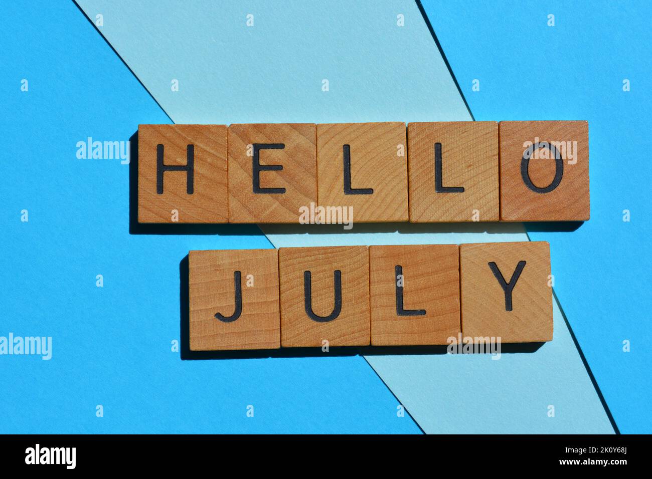 Hello July, words in wooden alphabet letters isolated on blue background Stock Photo