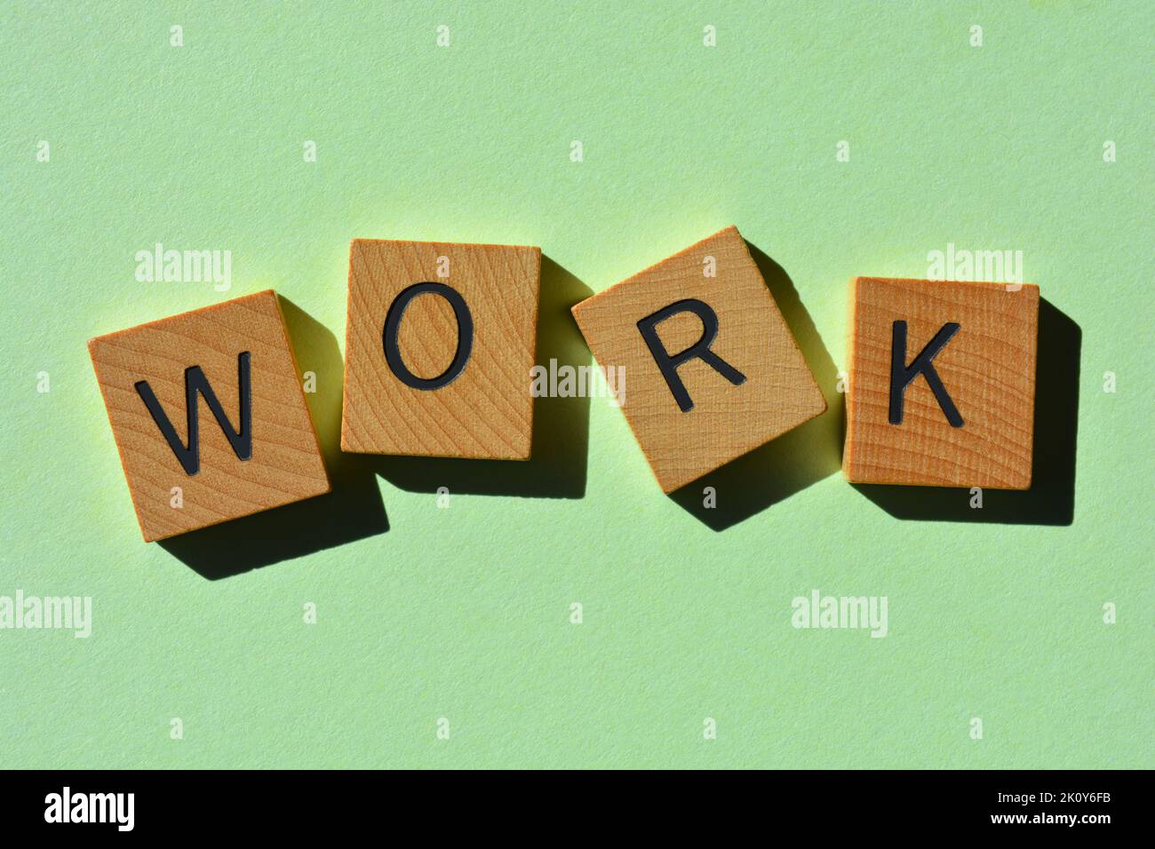 Work, word in wooden alphabet letters isolated on green background Stock Photo
