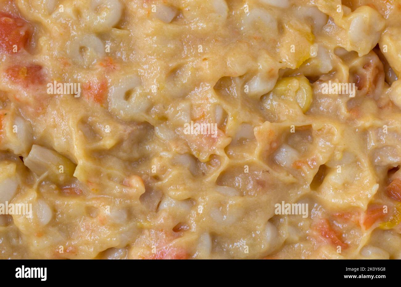 Close view of stirred macaroni and cheese baby food illuminated with natural light. Stock Photo