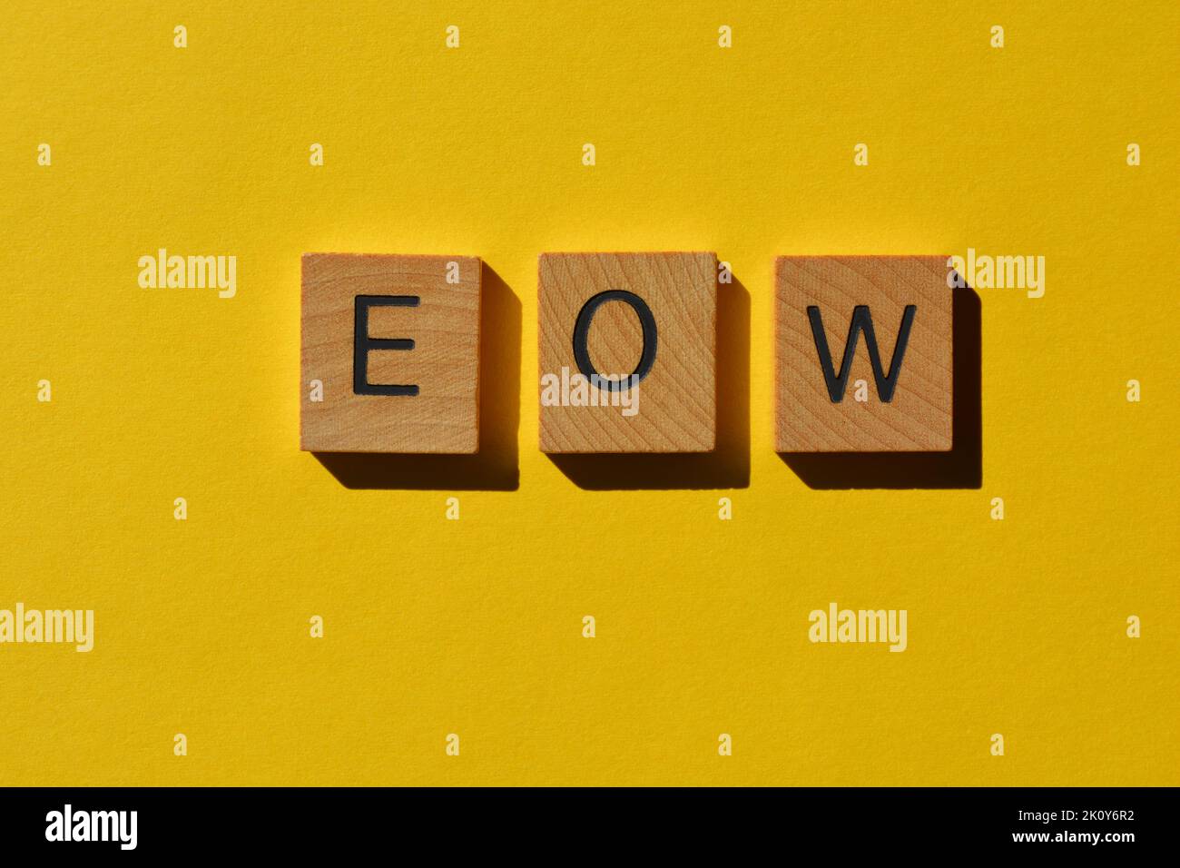 E O W, abbreviation used in text speak for End Of Week, wooden alphabet letters on bright yellow background Stock Photo