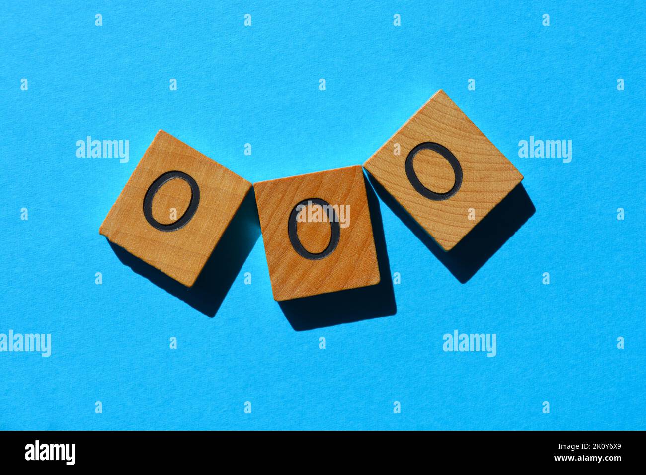 OOO, acronym for Out Of Office in wooden alphabet letters isolated on blue background Stock Photo