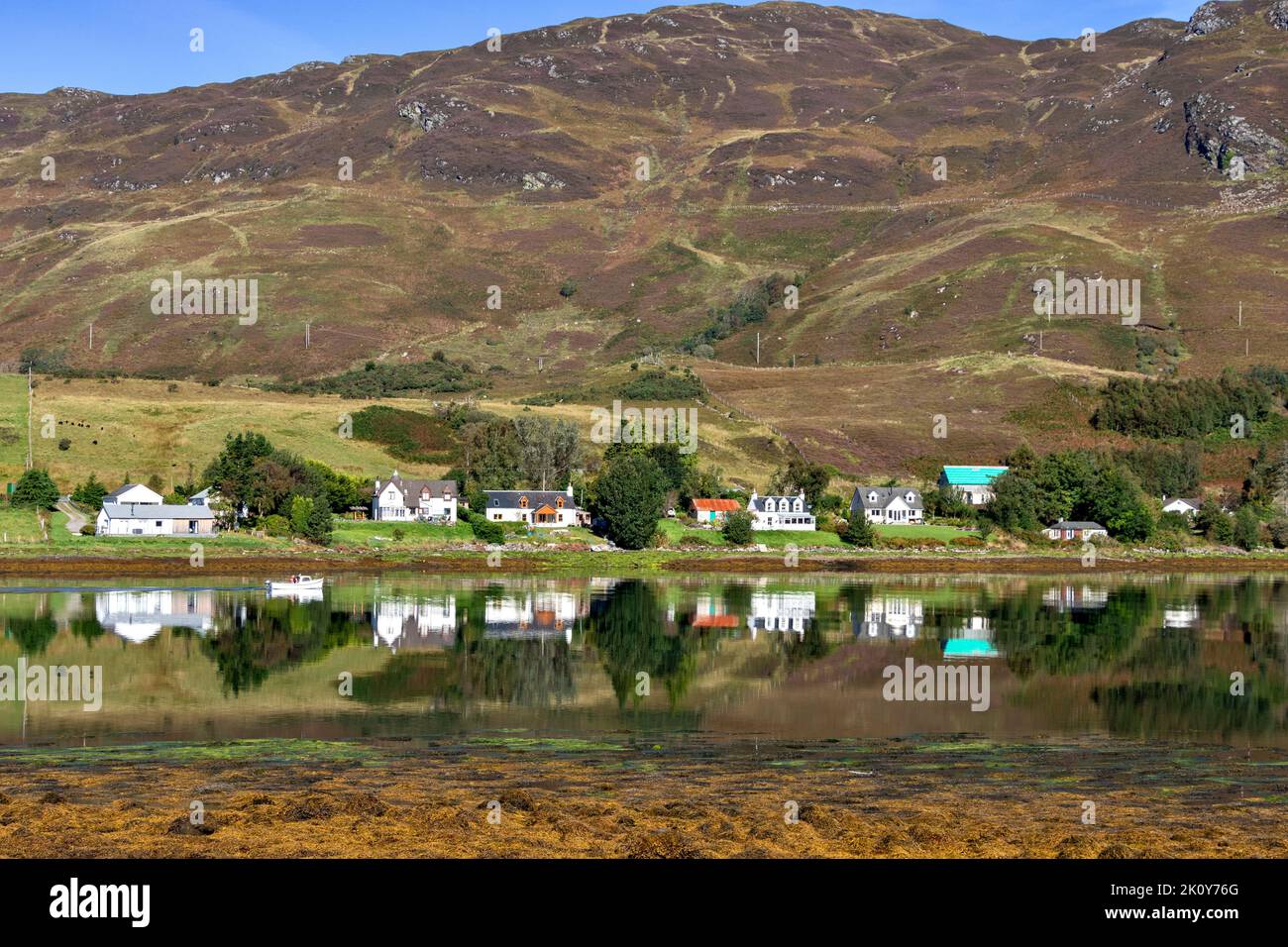 DORNIE KINTAIL SCOTLAND LATE SUMMER LOOKING ACROSS LOCH LONG TO HOUSES AND A PASSING SMALL FISHING BOAT Stock Photo