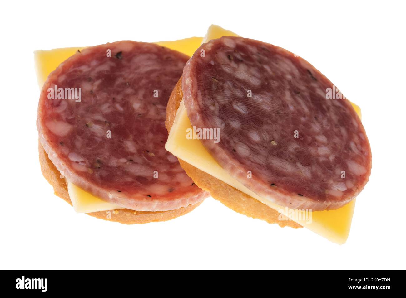 Side view of two snack crackers with dry salami and gouda cheese isolated on a white background. Stock Photo