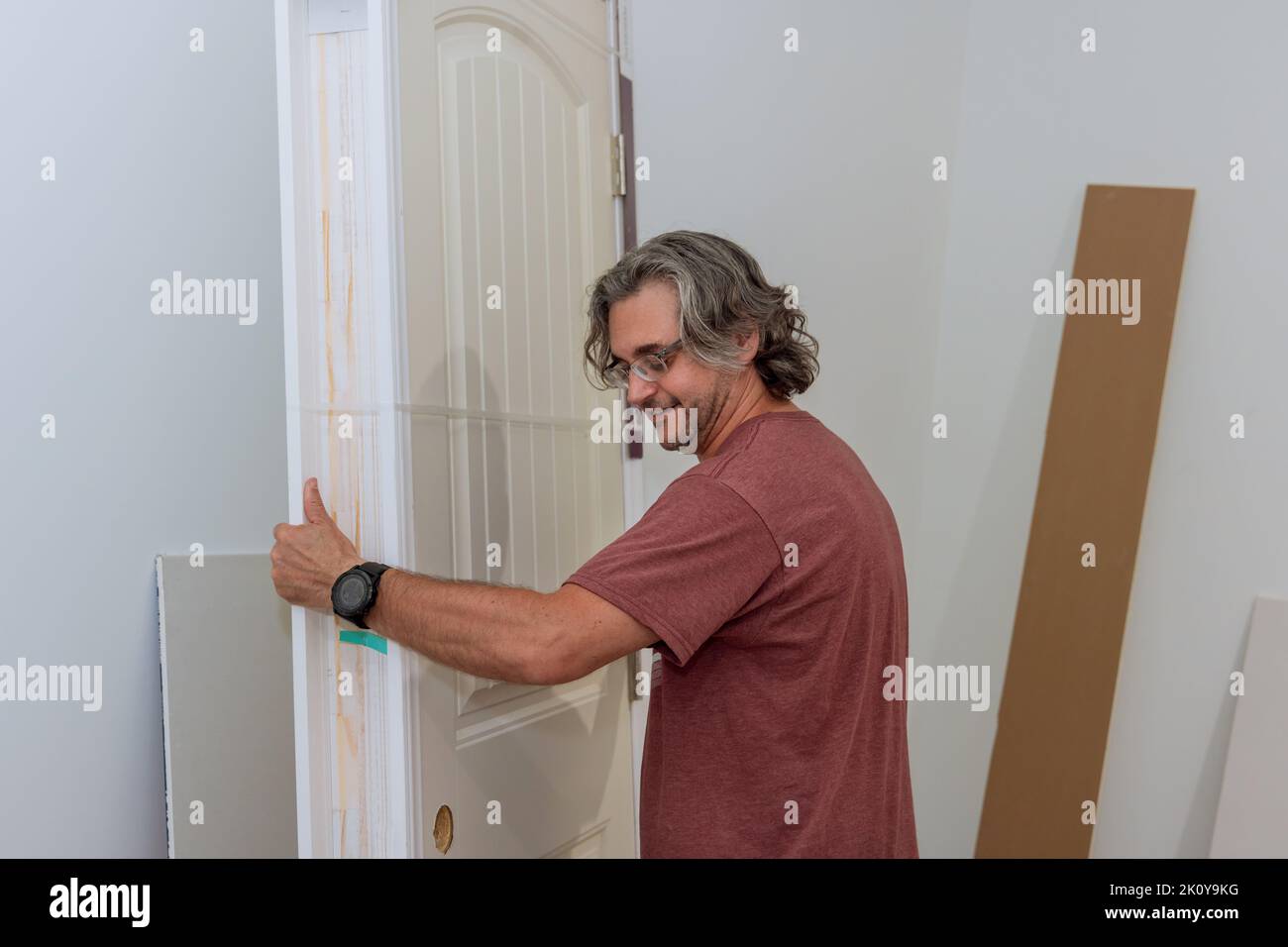 The worker holds the door in preparation for installation in a new house Stock Photo
