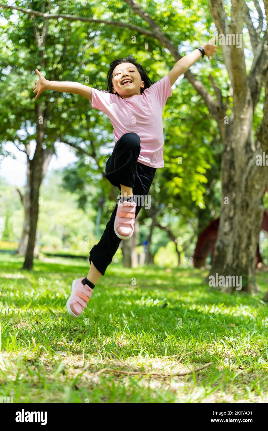 Portrait of child girl having fun jumping in the park outdoor. Stock Photo