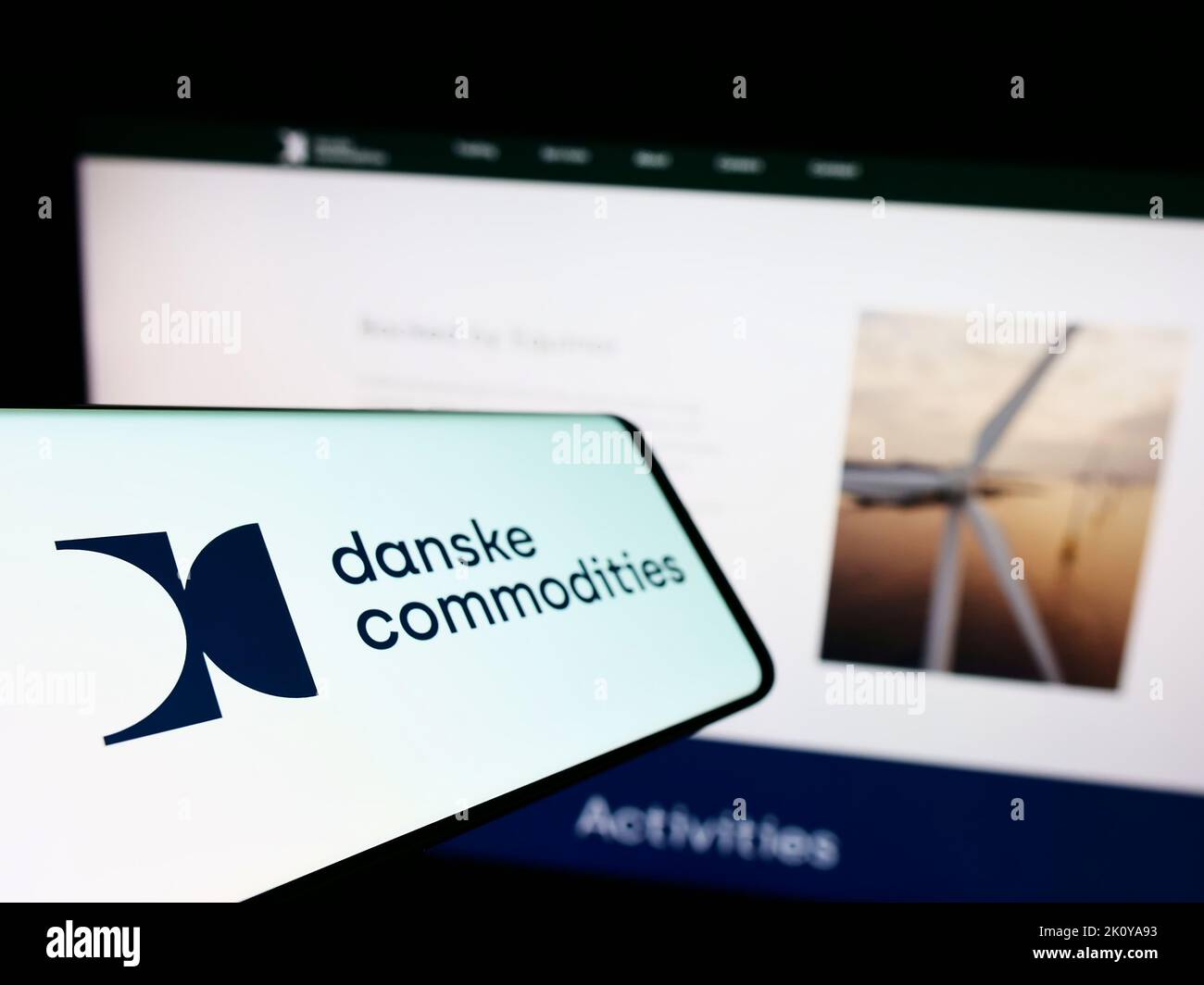 Mobile phone with logo of energy trading company Danske Commodities AS on screen in front of business website. Focus on left of phone display. Stock Photo
