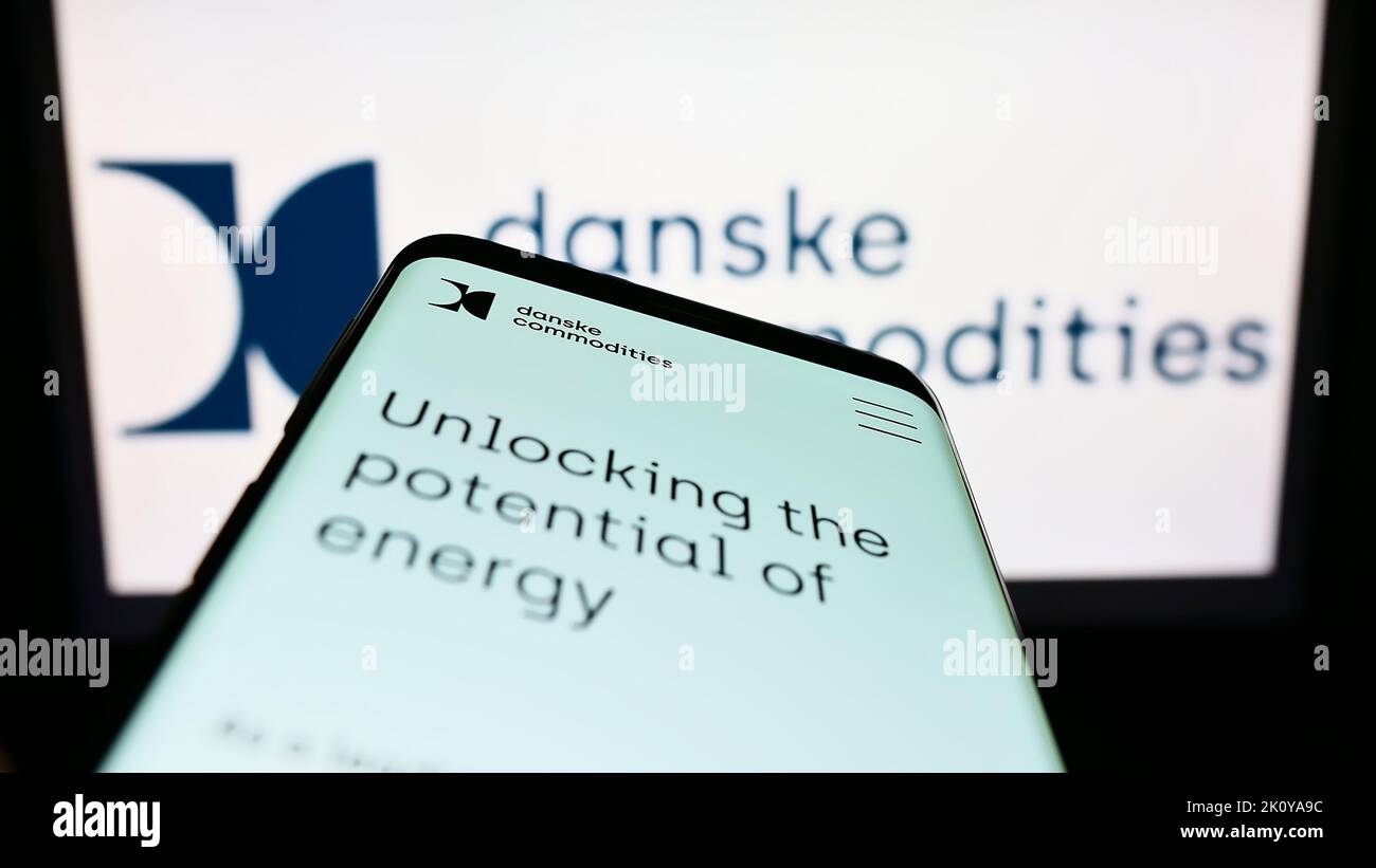 Smartphone with website of energy trading company Danske Commodities AS on screen in front of business logo. Focus on top-left of phone display. Stock Photo