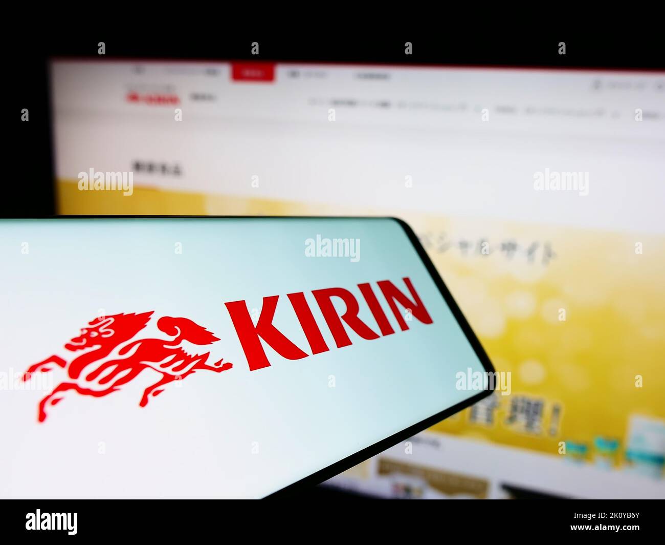 Smartphone with logo of Japanese Kirin Brewery Company Limited on screen in front of business website. Focus on center of phone display. Stock Photo