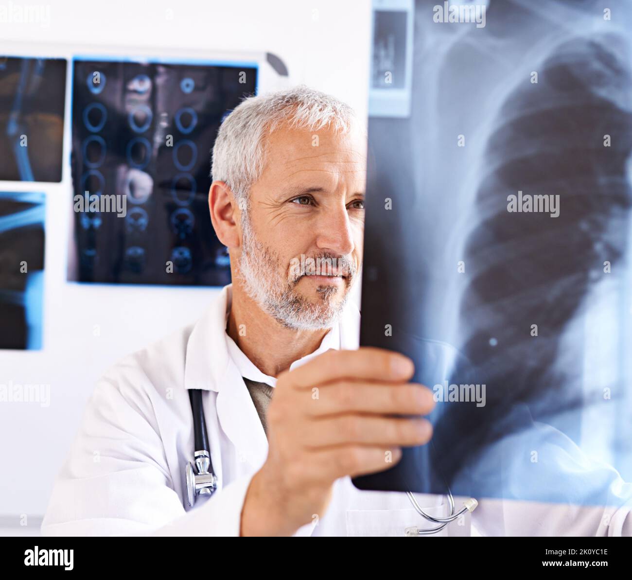 Hes an expert radiologist. a mature male doctor looking at a x-ray image at a hospital. Stock Photo