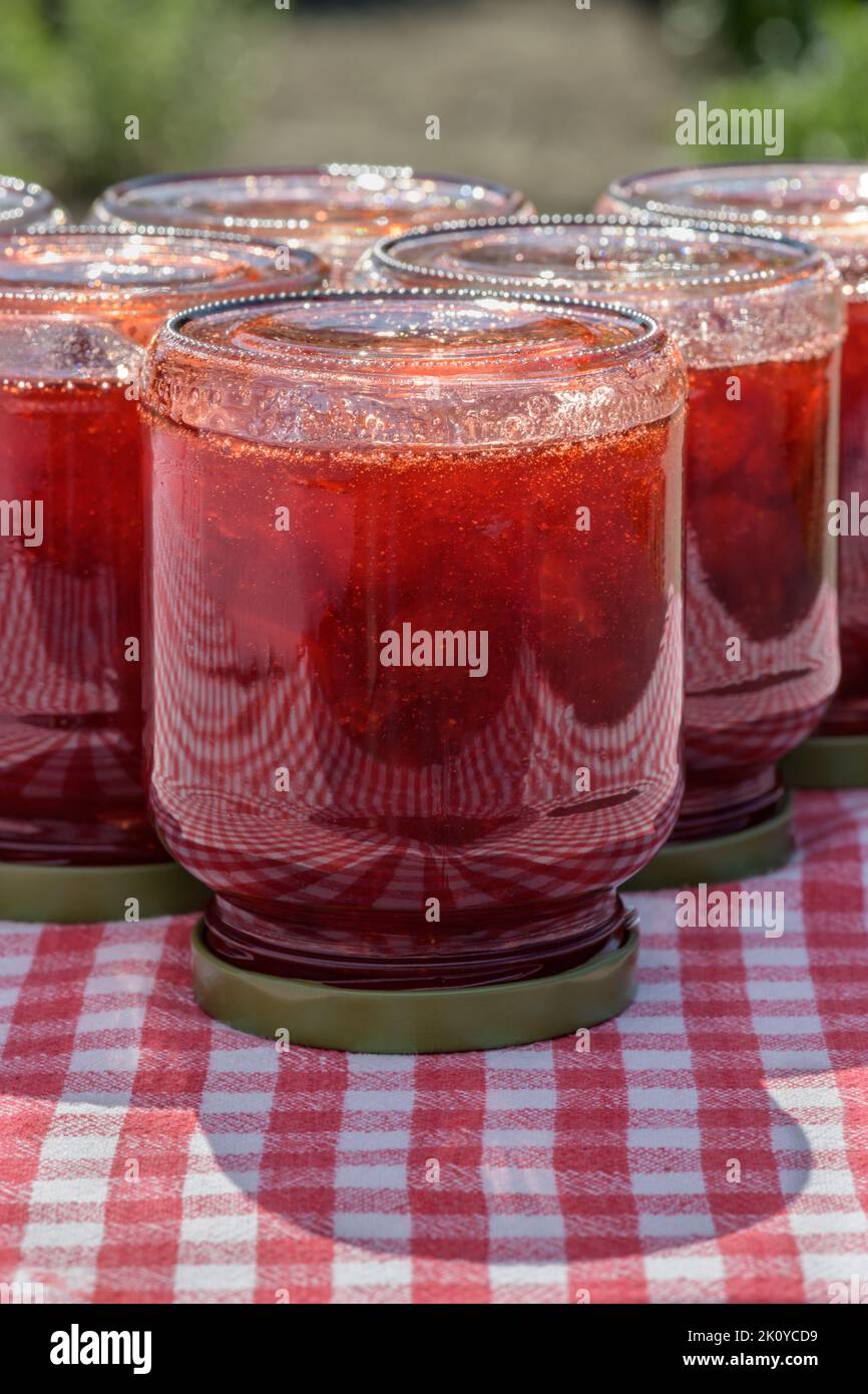 Glass jars with fresh homemade strawberry jam standing upside down on a