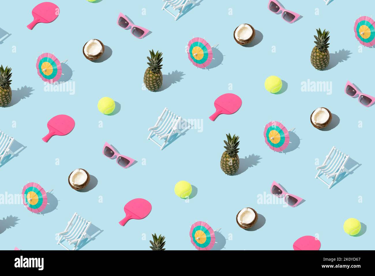 Summer pattern with colorful objects - pineapple, coconut, sunglasses, cocktail umbrella, tennis ball and racket, and beach chair on blue background. Stock Photo