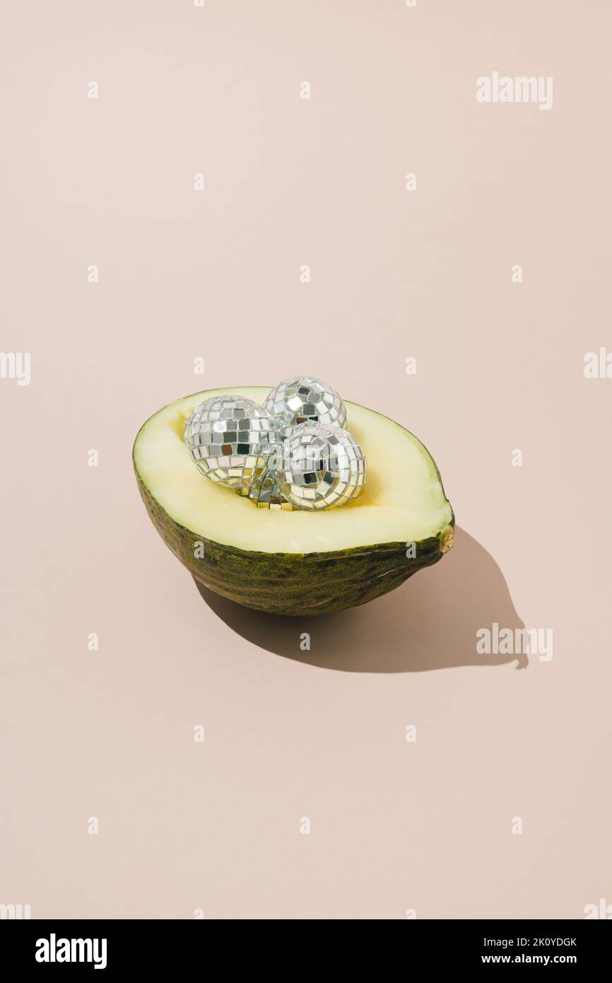 Disco balls in green melon in half of green melon on pink background. Stock Photo