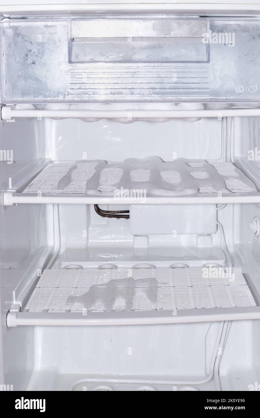Defrost Freezer. shelves and food container covered with melting ice