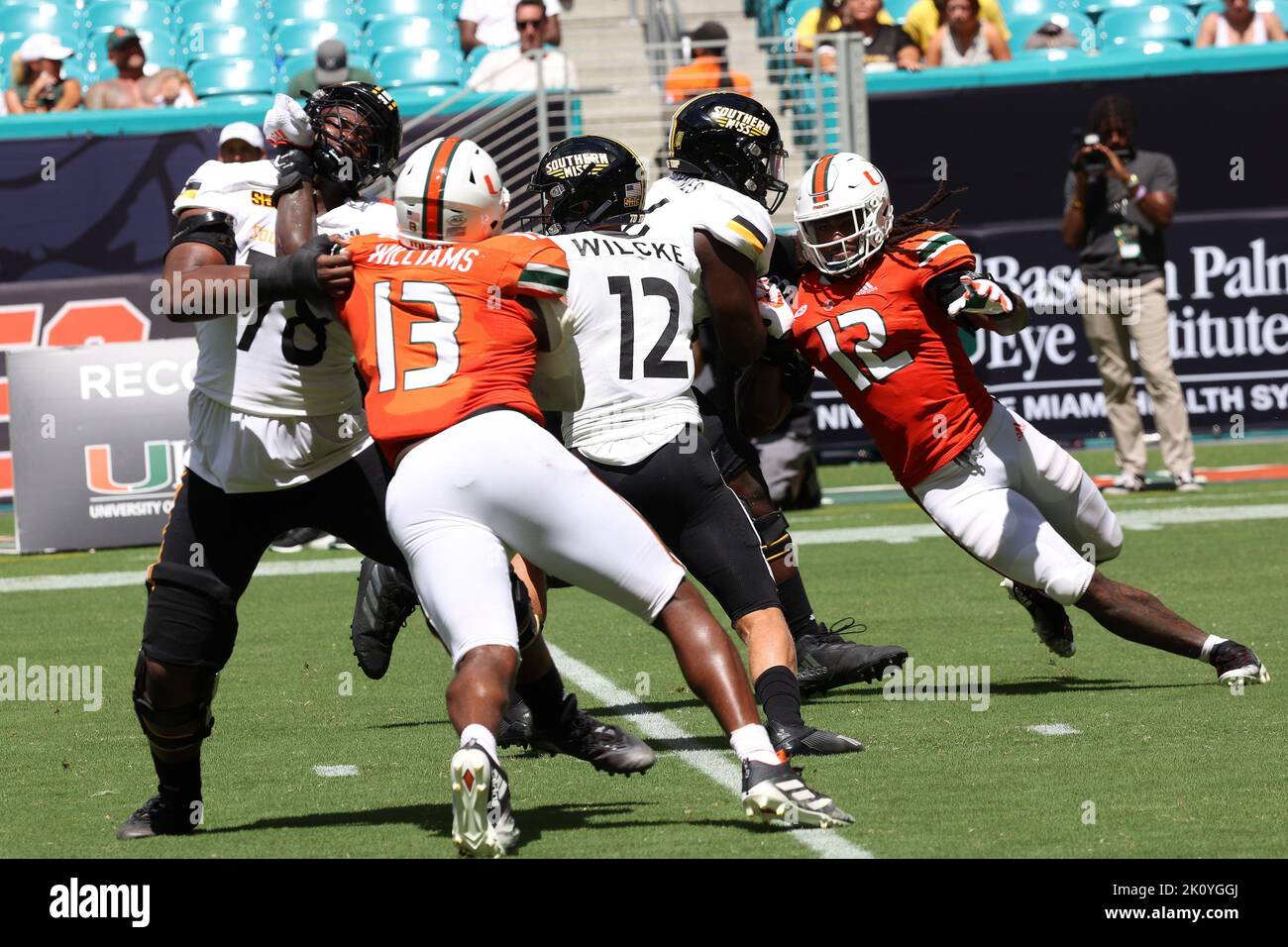 Southern Miss Golden Eagles left tackle Calvin McMillan (78) protects  quarterback Zach Wilcke (12) against the pass rush of Miami Hurricanes  defensive end Chantz Williams (13) at Hard Rock Stadium on September