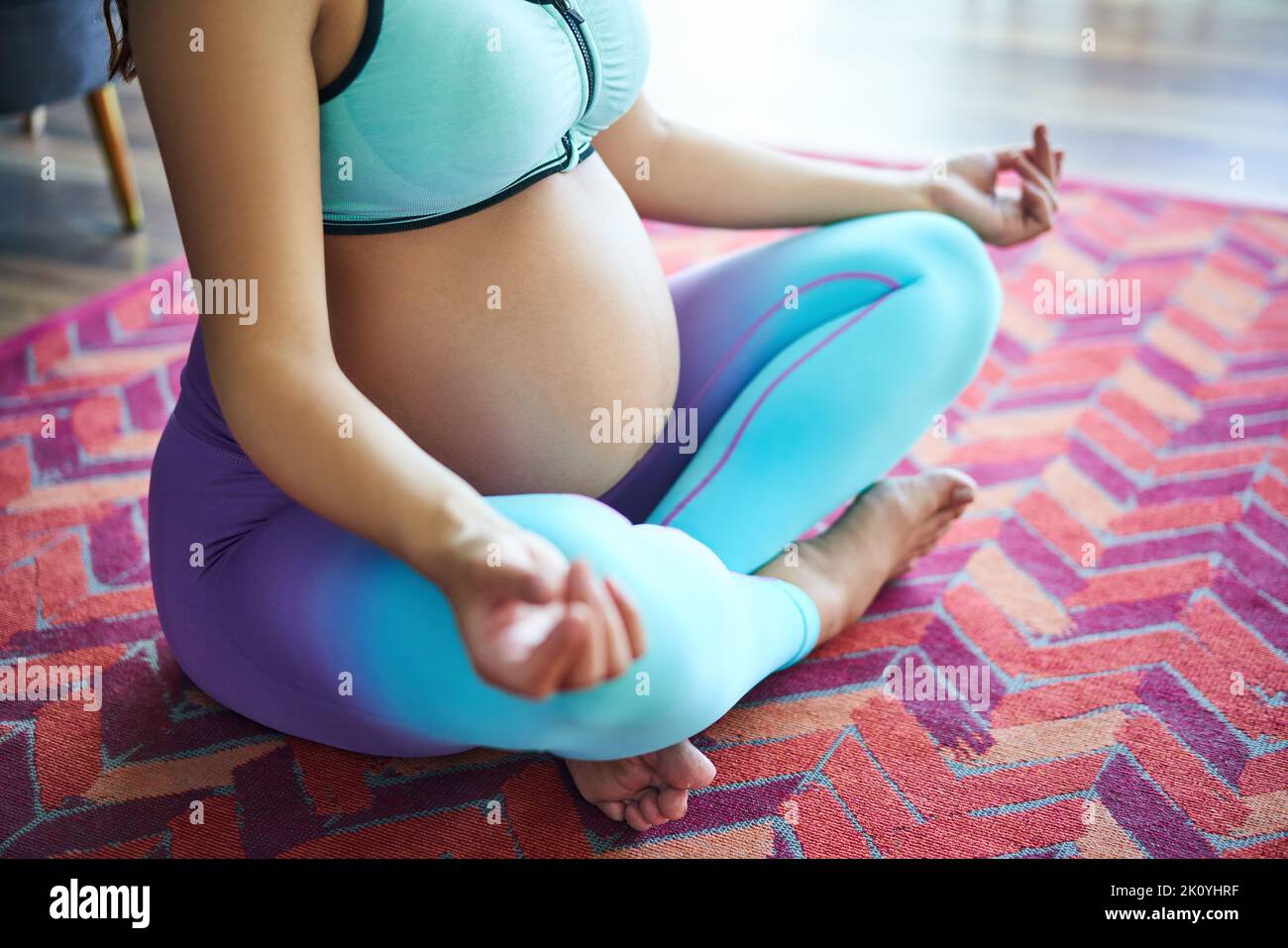 Close-up of pregnant sporty woman practicing yoga, meditating in Lotus pose Padmasana. Conscious motherhood. Healthy lifestyle and baby care concept Stock Photo