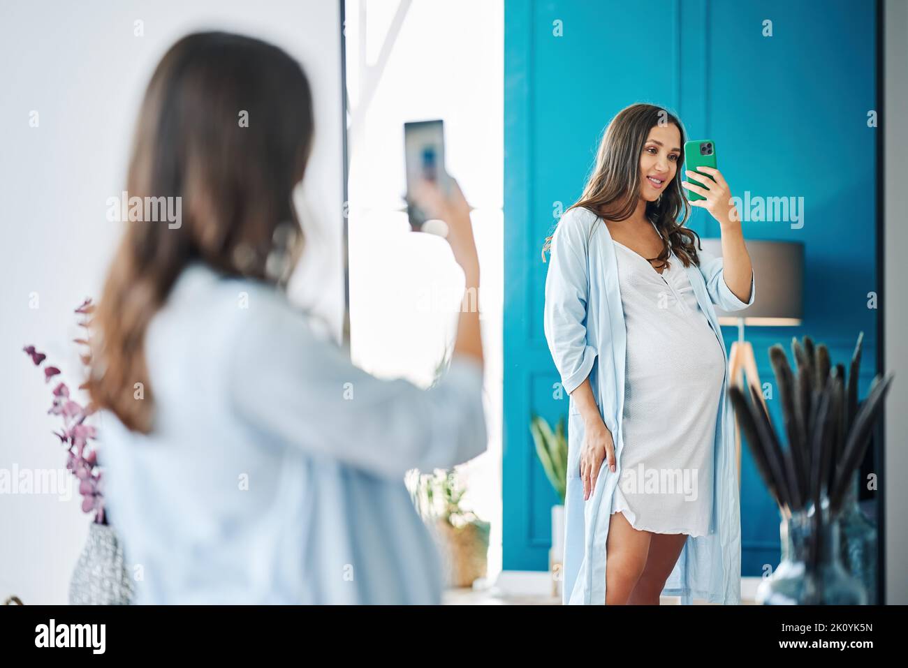 Portrait of smiling pregnant woman taking mirror selfie at modern home. Pregnancy, motherhood, expectation and tenderness concept Stock Photo