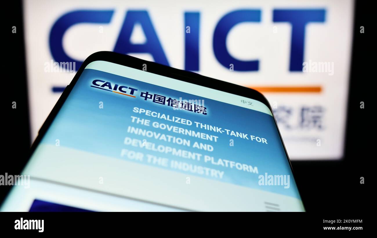 Mobile ohone with website of Chinese communications research institute CAICT on screen in front of logo. Focus on top-left of phone display. Stock Photo