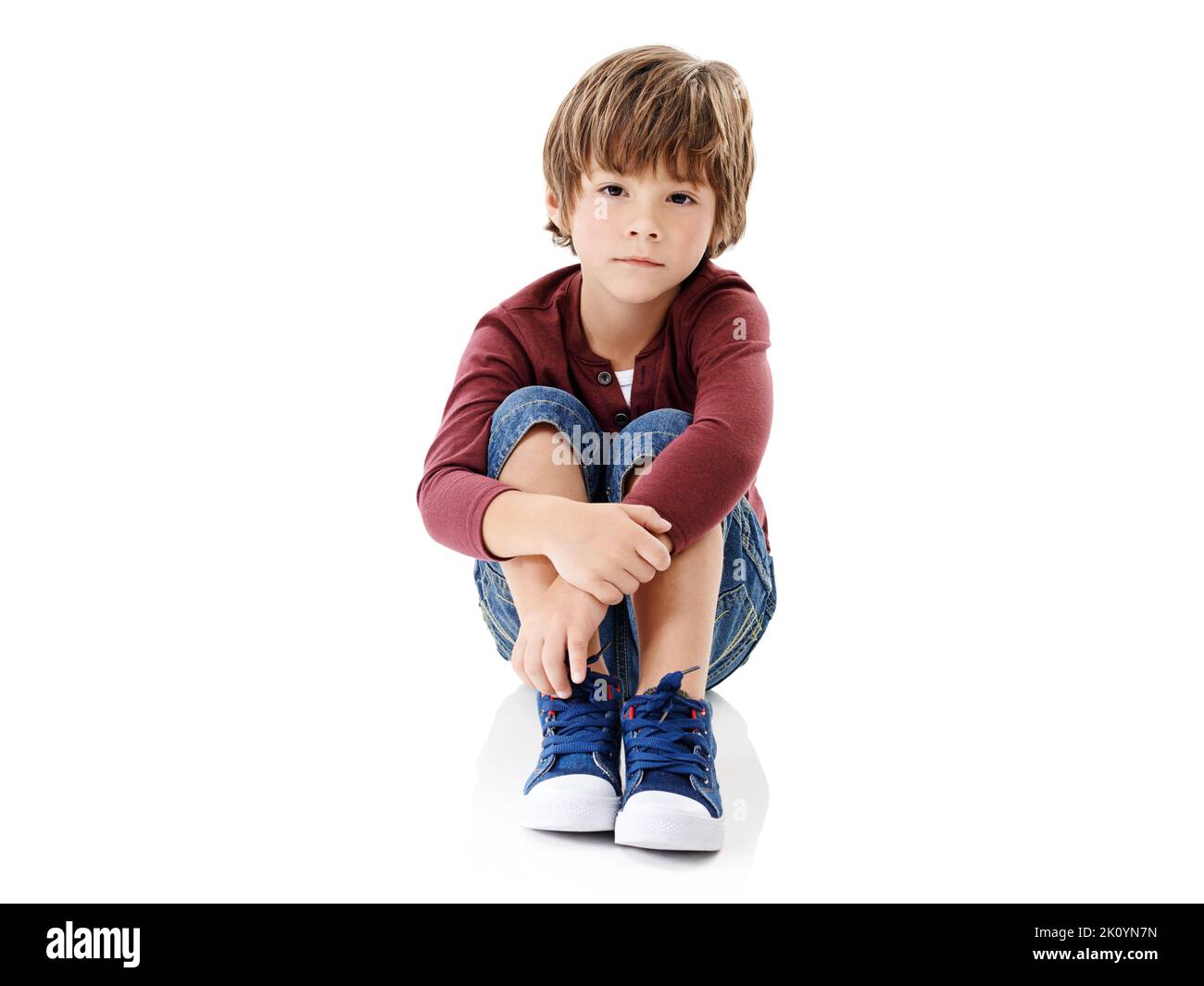 Where is everyone. Studio shot of a cute little boy hugging his knees against a white background. Stock Photo