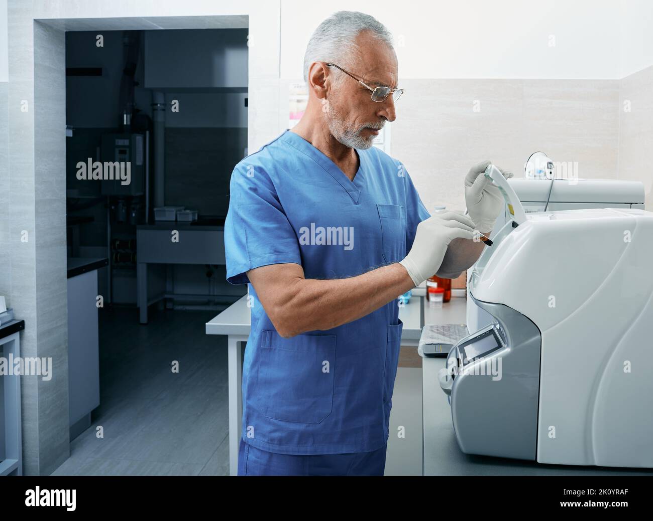 Laboratory assistant loading blood sample into ESR analyzer. Erythrocyte sedimentation rate test Stock Photo