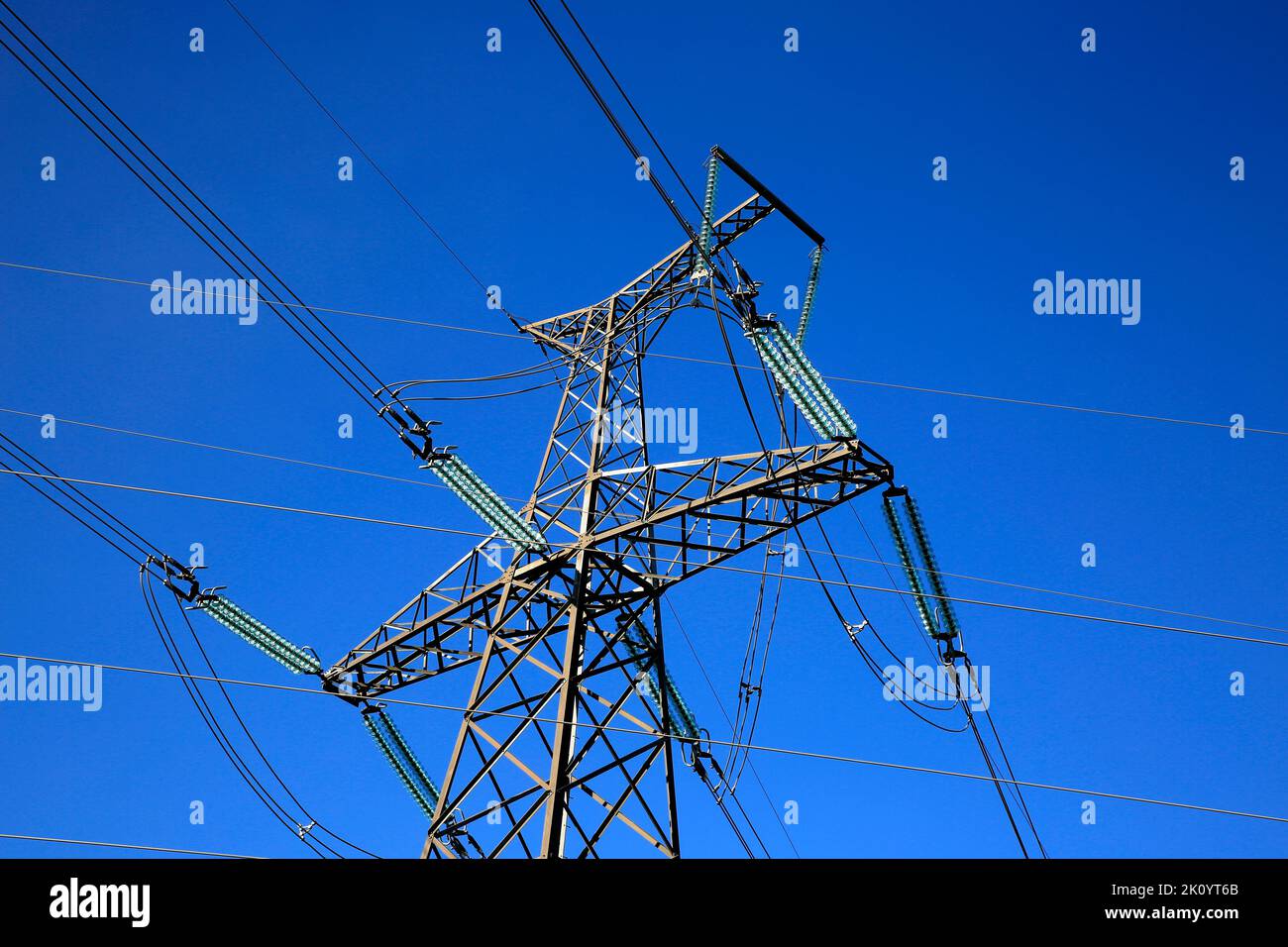 Overhead transmission line tower against blue sky. Stock Photo