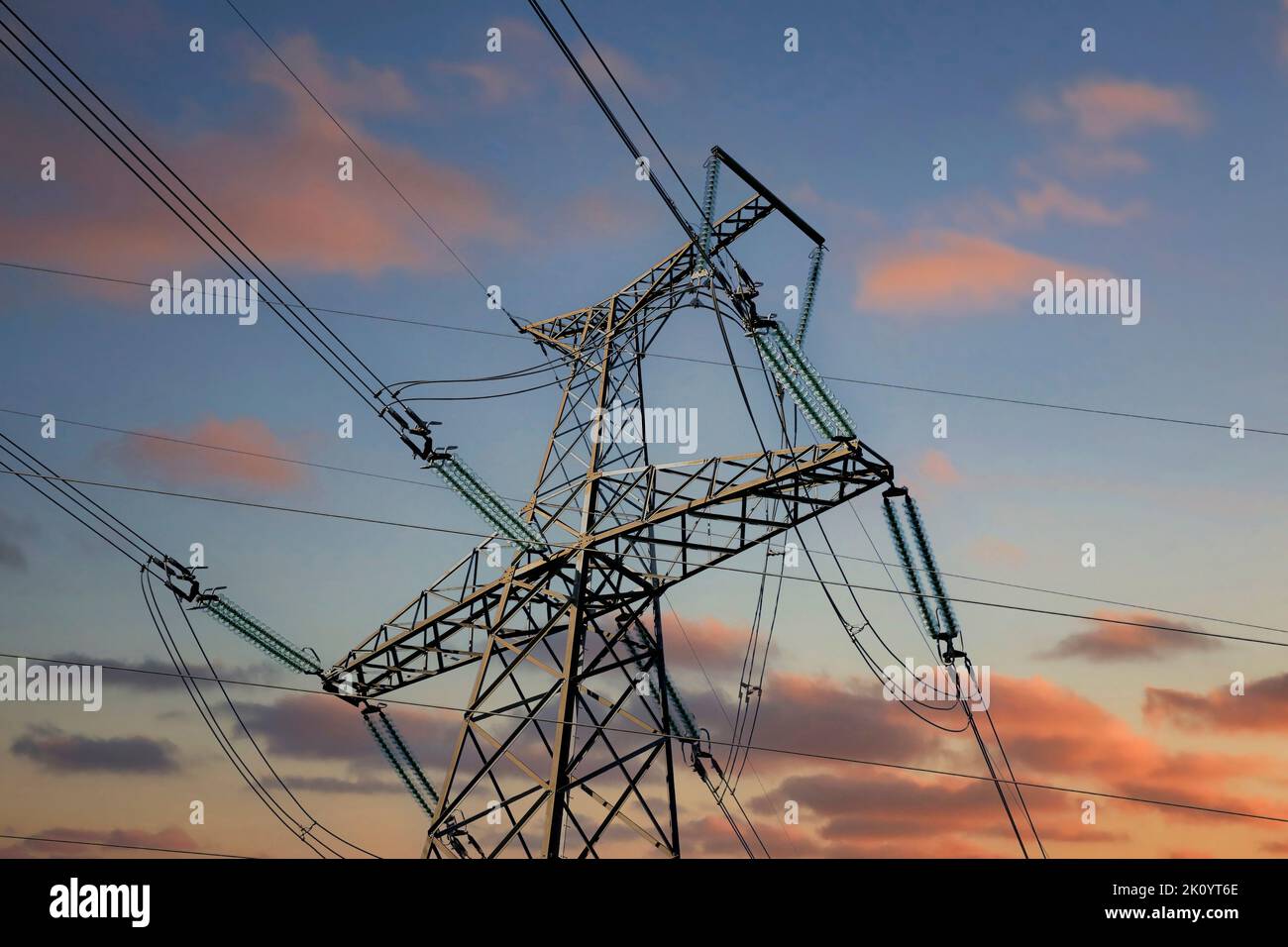 Overhead transmission line tower against sunset sky, detail. Stock Photo