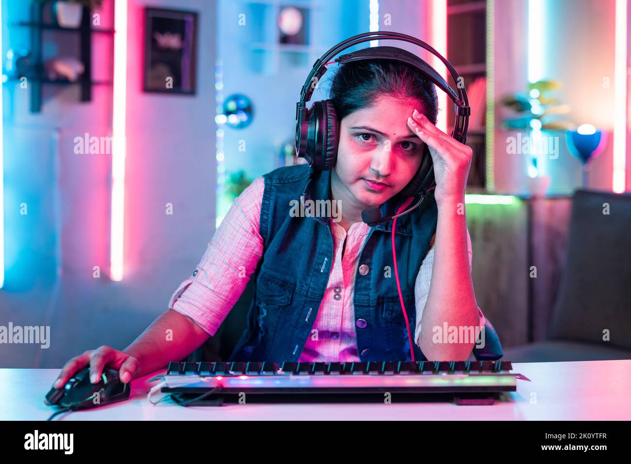 worried gamer with headphone due to loss while playing online video game by looking camera at home - concept of live streamer, leisure activities and Stock Photo