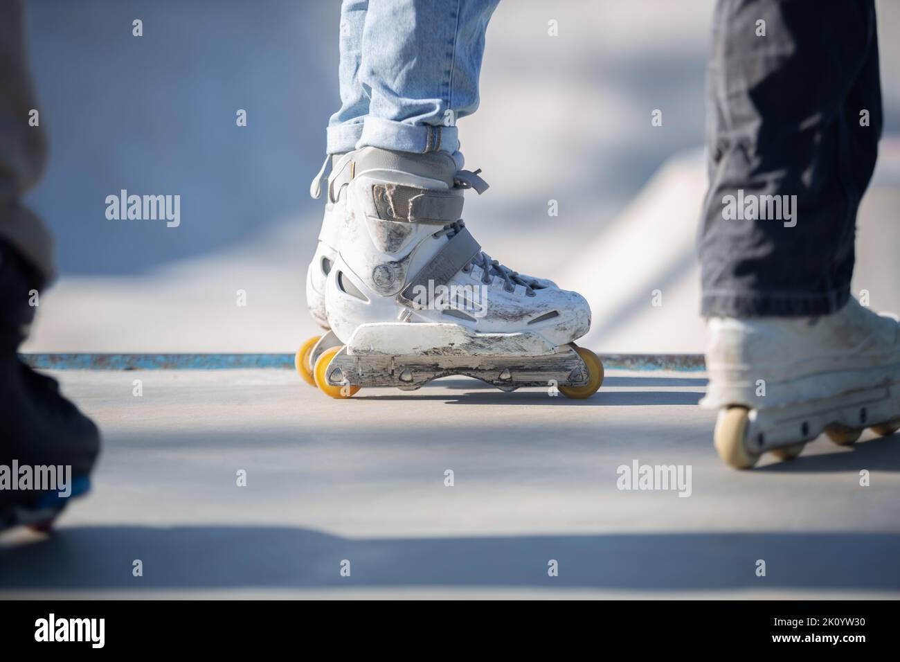 Roller blader wearing white aggressive inline skates in skatepark