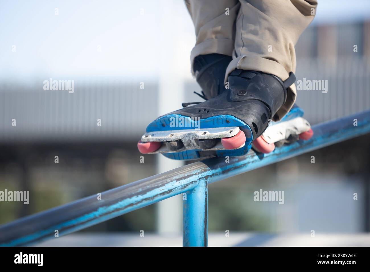 Inline skater grinds on rail in skatepark. Roller blader grinding on