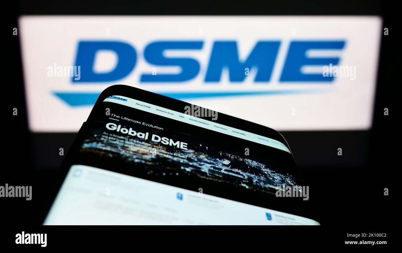 Mobile phone with website of Daewoo Shipbuilding and Marine Engineering (DSME) on screen in front of logo. Focus on top-left of phone display. Stock Photo