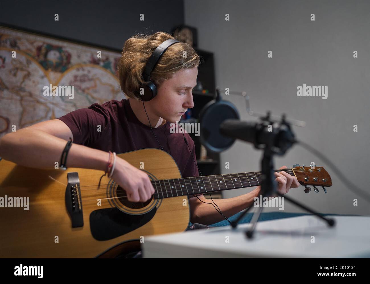 Home sound studio young teenager portrait playing guitar in Headphones
