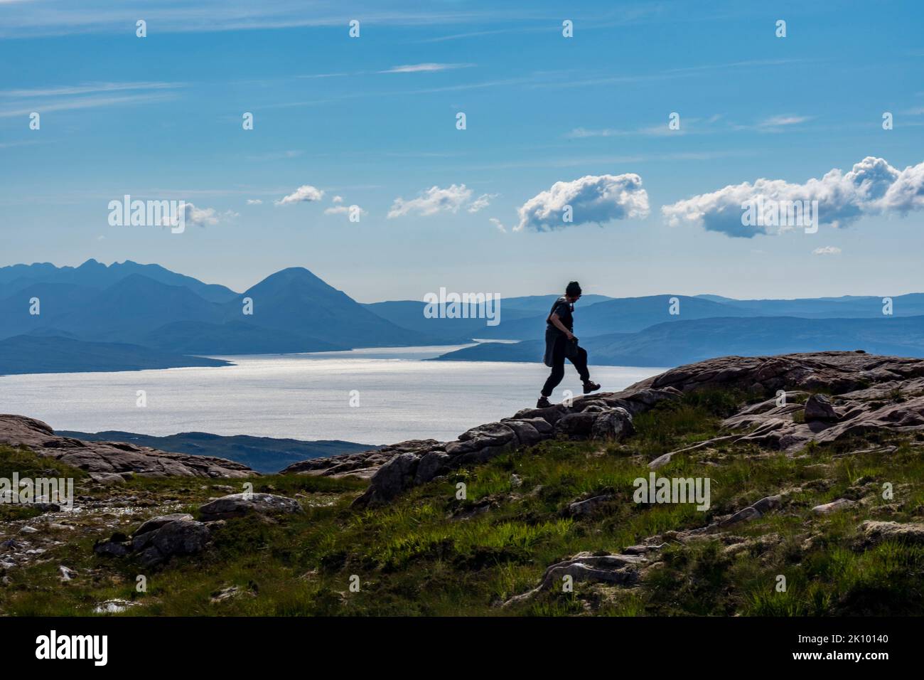 woman walking at pass of the cattle with isle of  skye in background, applecross, scotland, uk Stock Photo